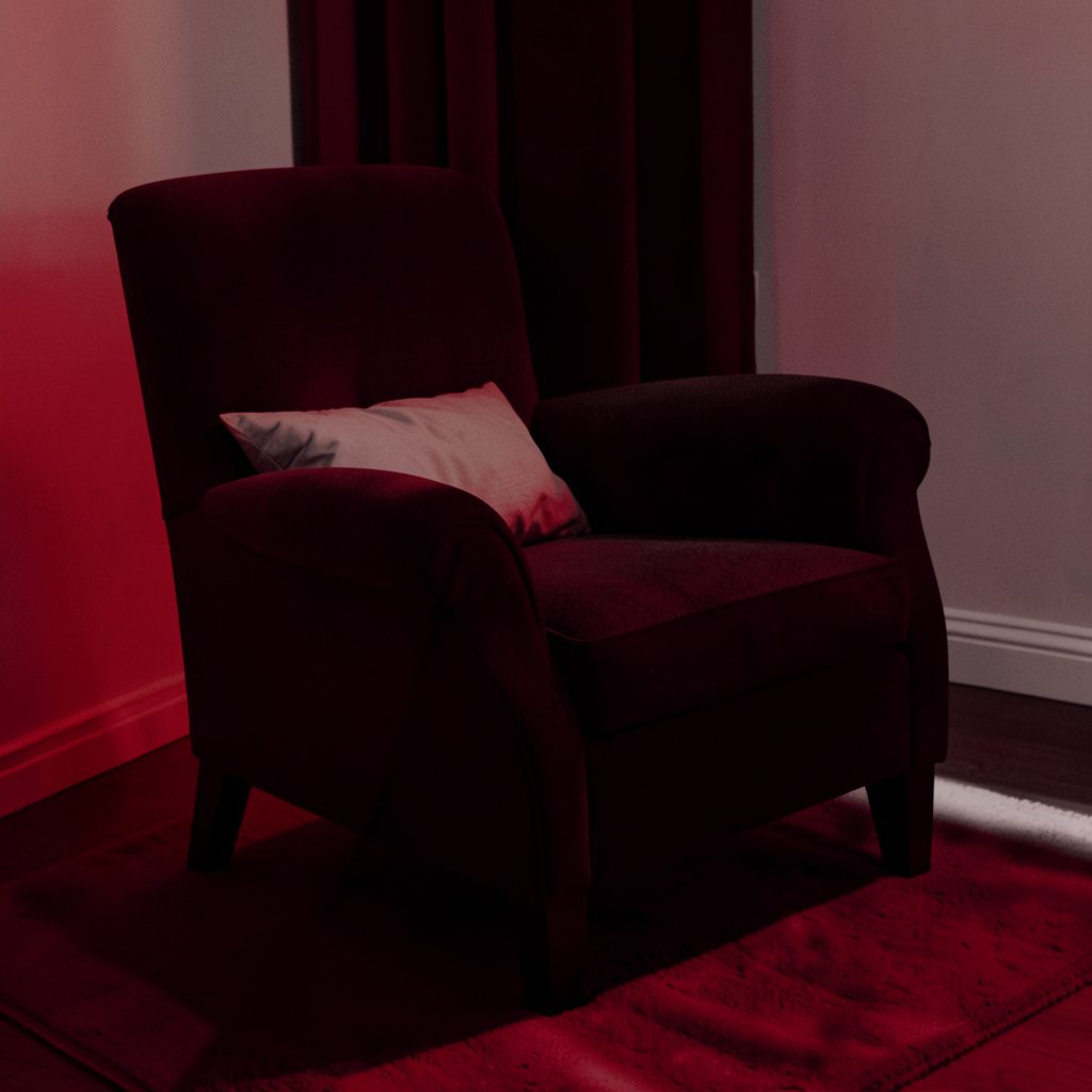 A warm duotone photograph of a convertible chair bed in a cozy interior setting, rendered in deep teal and soft coral, suggesting versatile home furnishing.